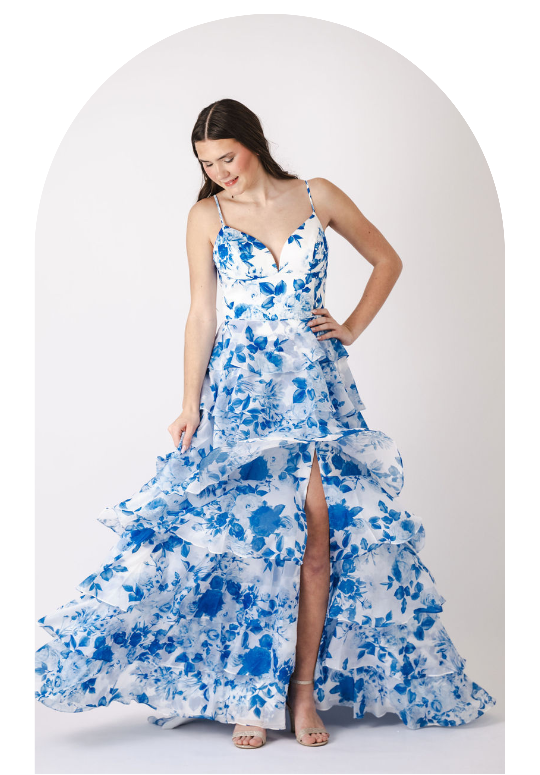 Woman in a blue-and-white floral gown posing against a white backdrop