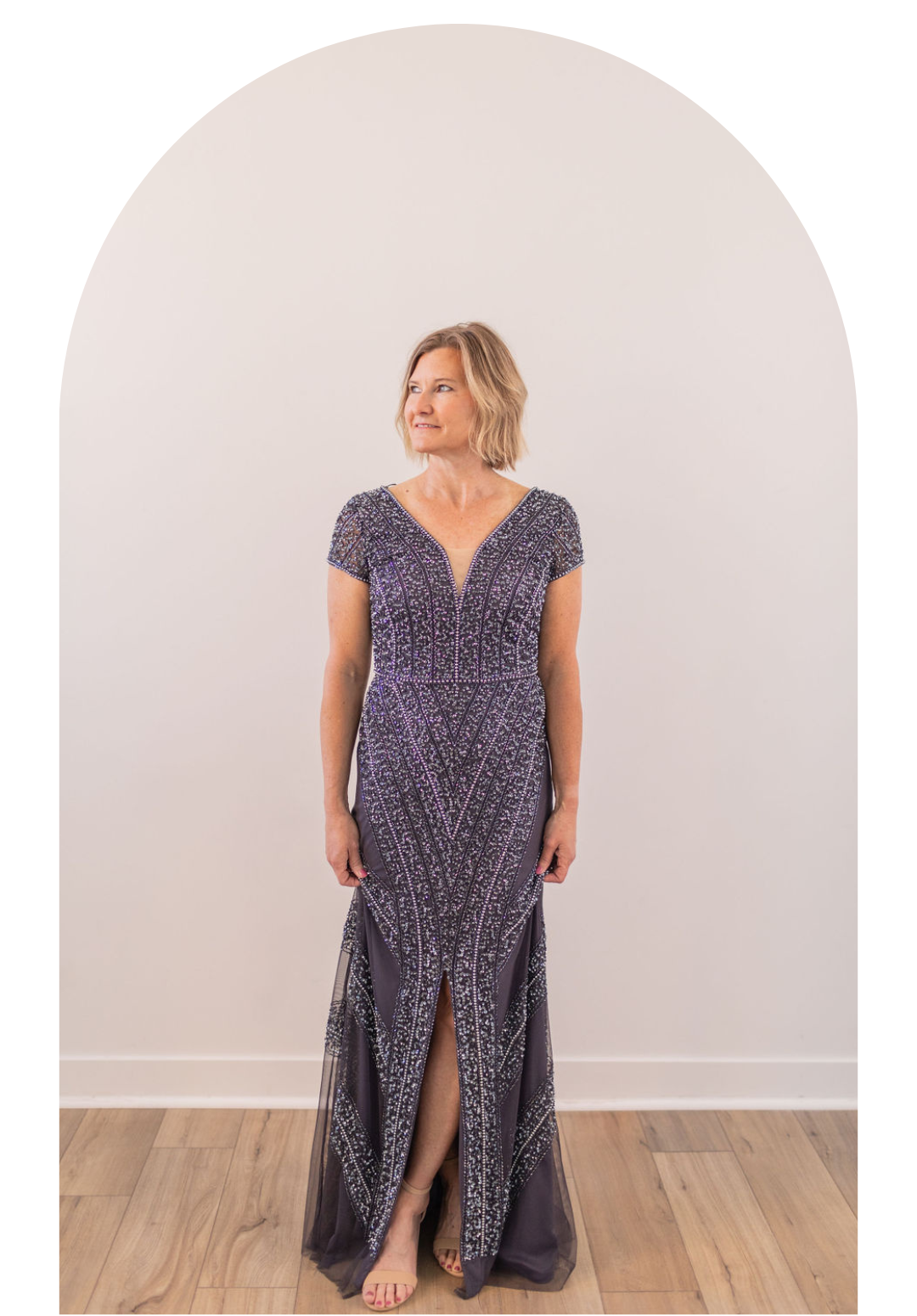 Woman in a navy floral dress standing in an arched alcove on a wooden floor.