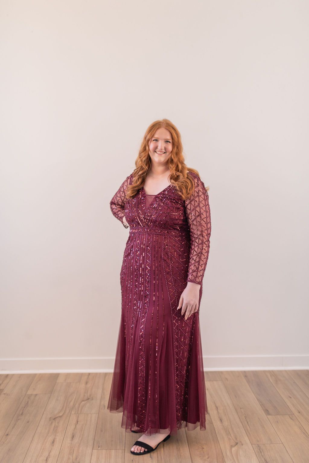 Woman in a navy patterned maxi dress standing against a white wall on a wooden floor