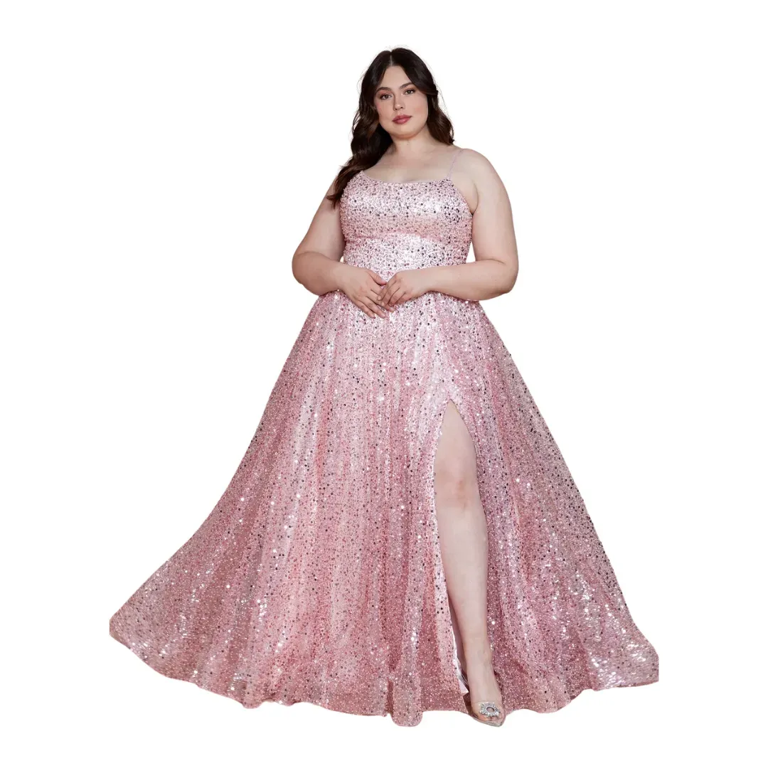 Woman in a sparkling pink strapless gown with a thigh slit, standing against a white background.