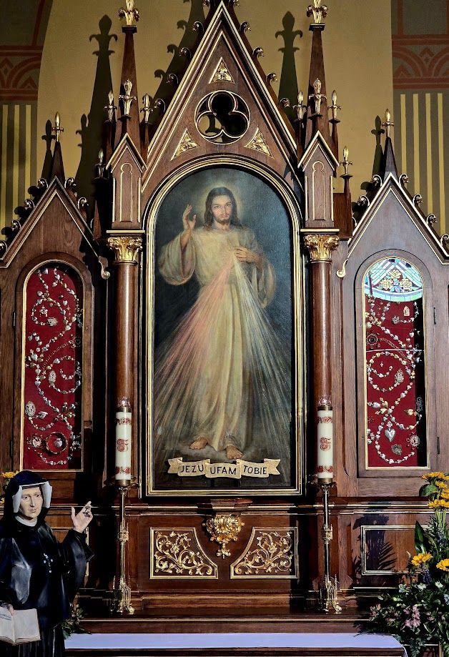 Religious altar painting of Jesus in a church, framed by ornate Gothic decorations and red side panels