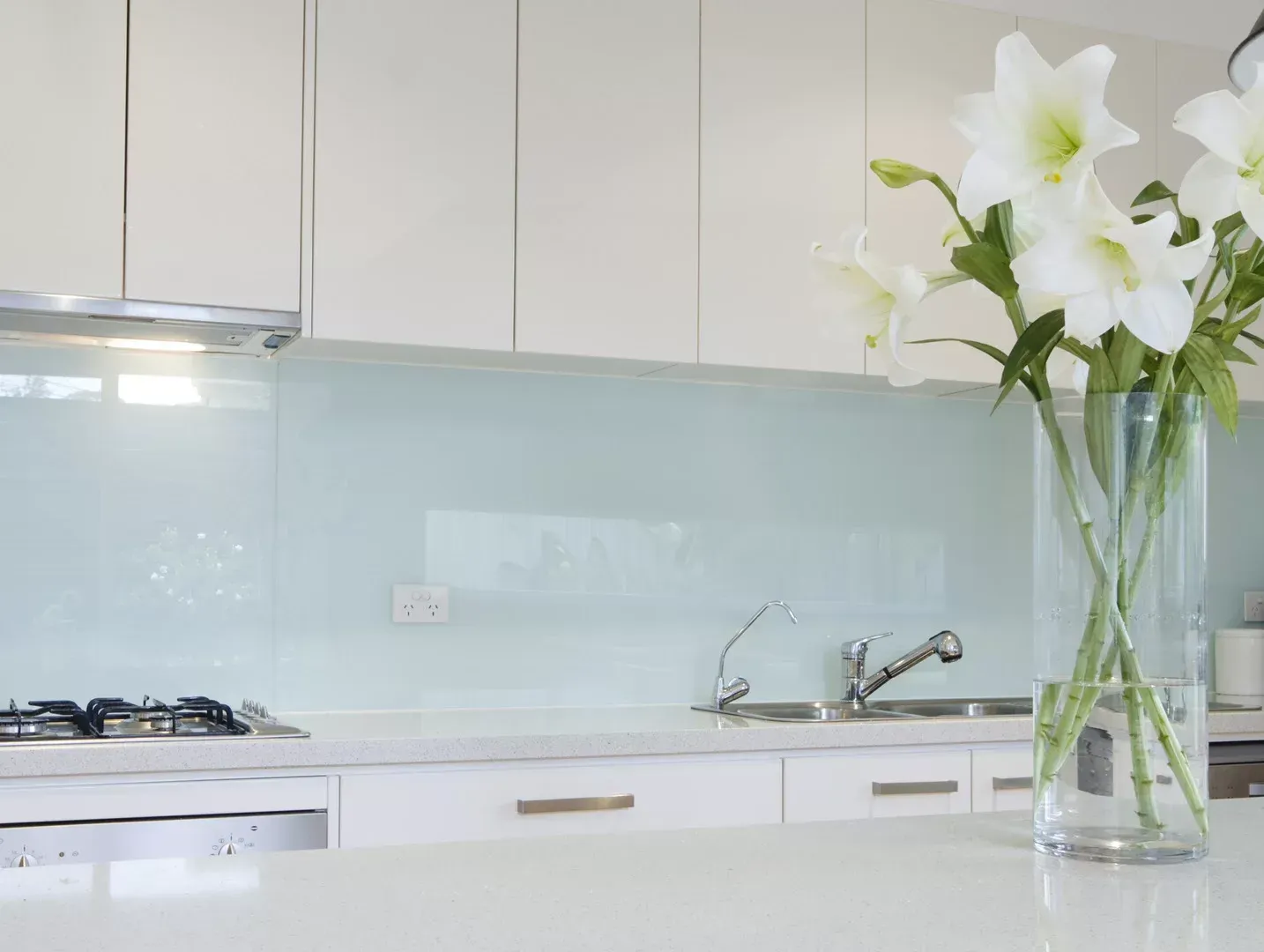 A kitchen with white cabinets and a vase of flowers on the counter