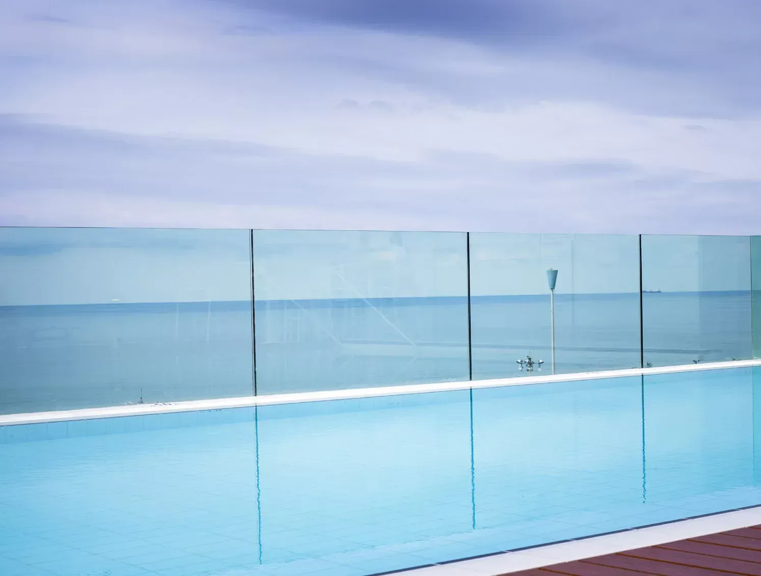 A swimming pool with a glass fence overlooking the ocean
