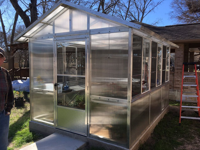 A greenhouse is being built in the backyard of a house.