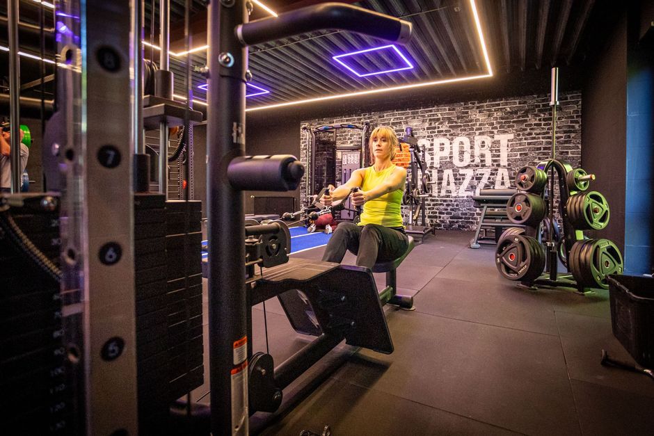 Een vrouw zit op een machine in een sportschool.