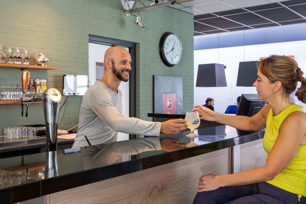 Een man serveert een drankje aan een vrouw in een bar.
