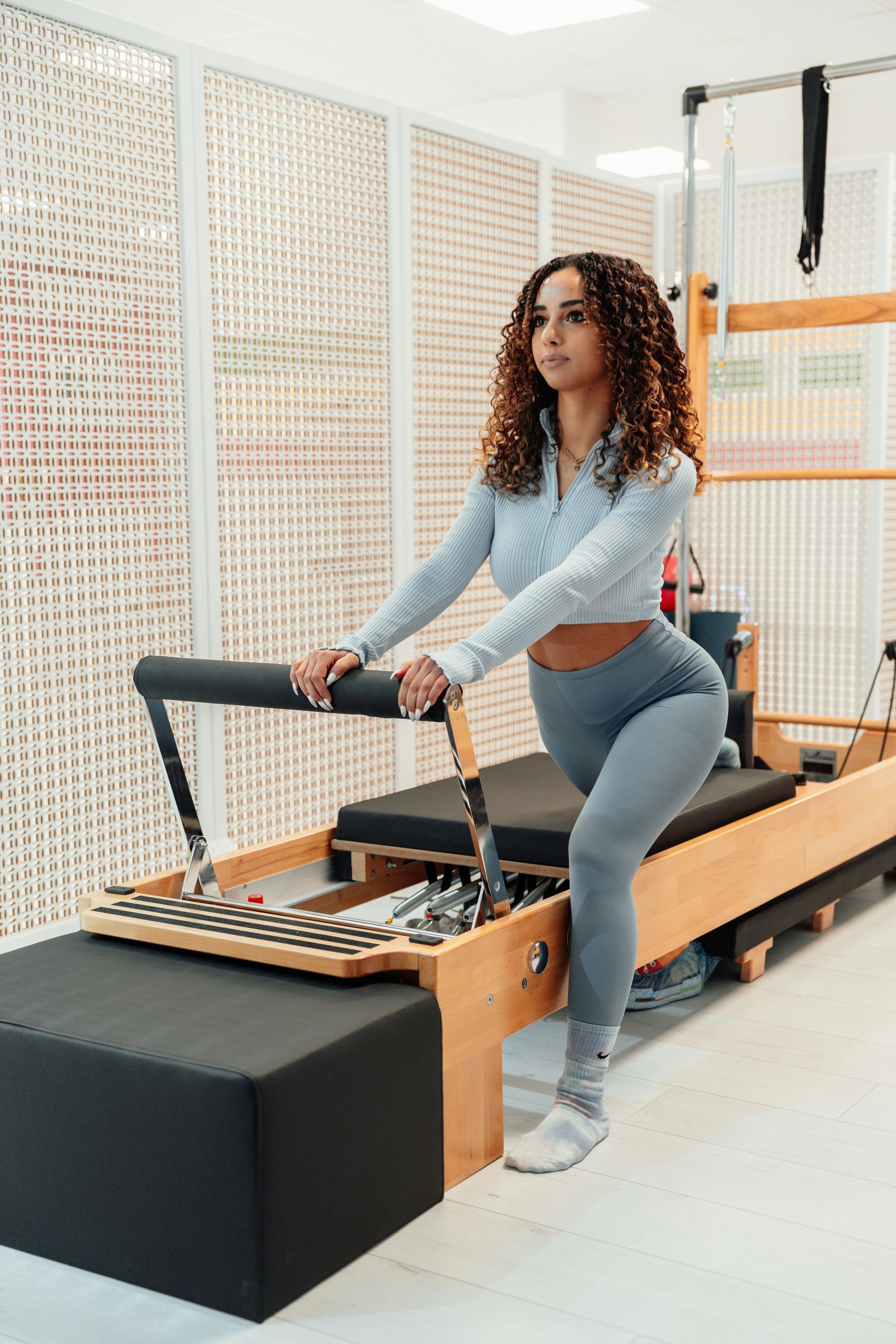 Een vrouw doet een yogahouding op een pilatesapparaat in een sportschool.