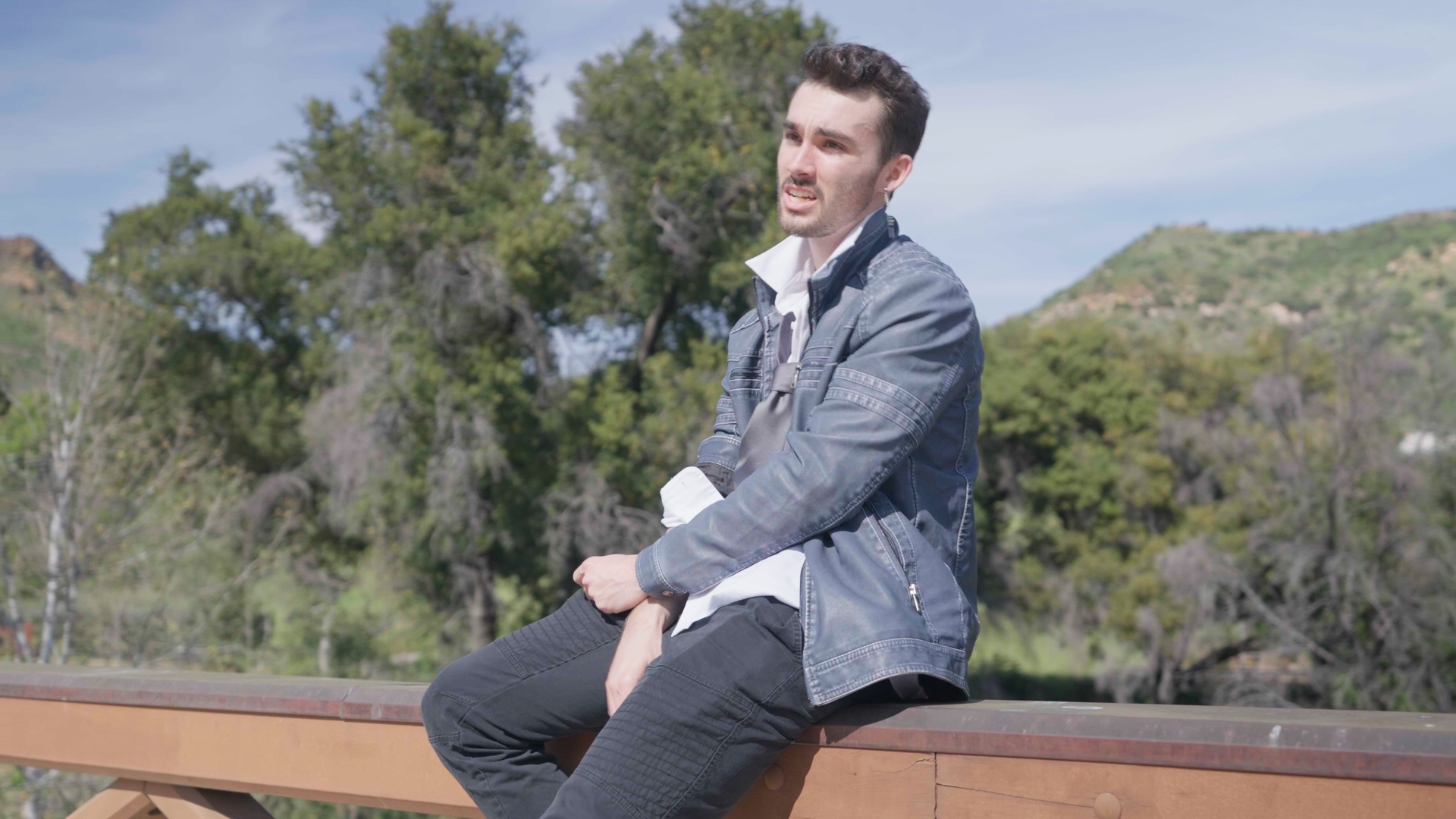 A man in a suit and tie is sitting on a wooden railing.