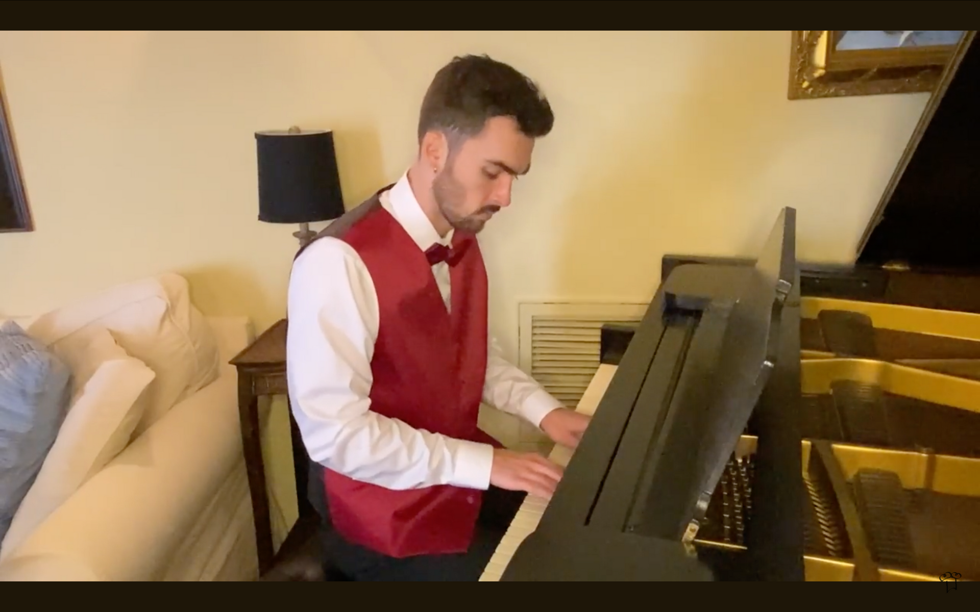 A man in a red vest and bow tie is playing a piano