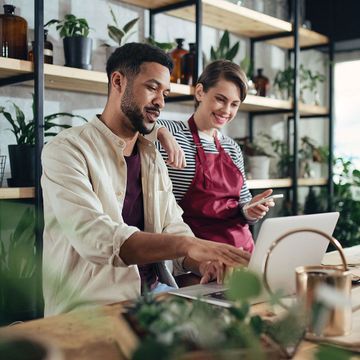 Shop assistants with laptop working in potted plant store, small business concept