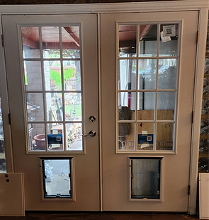 Two cream-colored French doors with installed pet doors. The doors have multiple glass panels and a porch view.