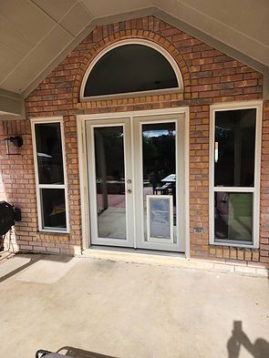 Brick exterior with arched window above French doors and two side windows; dog door.