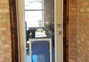 Dog door installed in glass door, brick exterior. White frame, dark wood trim.
