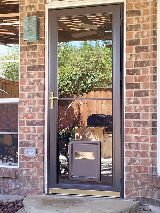 Brown storm door with reflective glass, brick wall, and a mailbox.