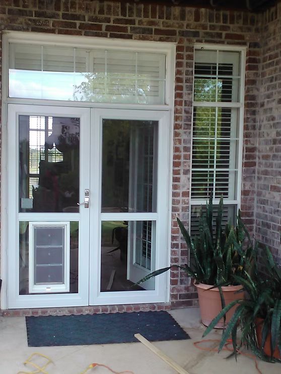 White double doors with dog door, sidelight, and transom window in brick facade.