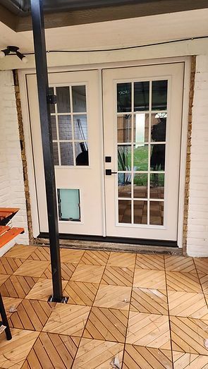 White French doors with pet door, on a tiled patio, with a black support beam.