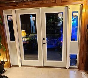 White French doors with sidelights. Pet door installed in the right sidelight. Interior setting, door open to outside.