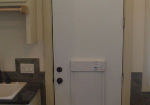 White door in a kitchen; features a security system panel.