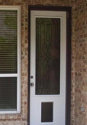 White door with decorative glass panel and pet door. Brick wall.