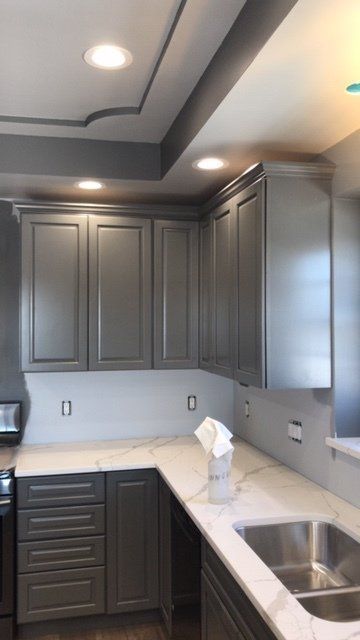 Modern kitchen with gray cabinets, white countertops, and a stainless steel sink