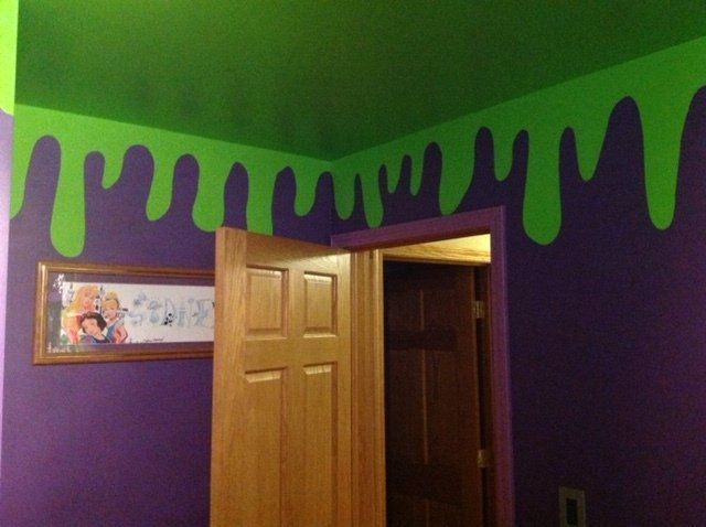 Purple bedroom with bright green dripping paint along the ceiling and an open wooden door.
