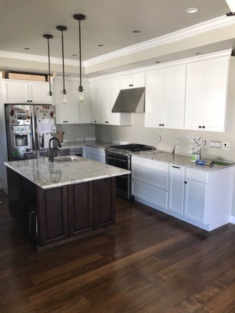 Modern kitchen with white cabinets, dark wood island, stainless appliances, and pendant lights