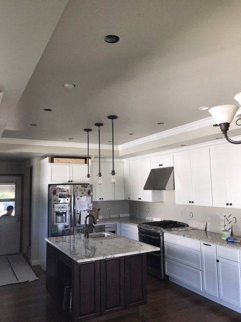 Modern kitchen with white cabinets, dark island, granite countertops, and pendant lights