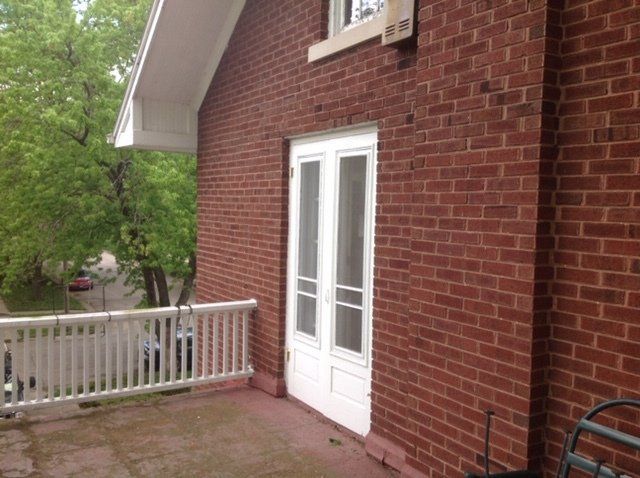 Brick apartment patio with white double doors, railing, and trees outside