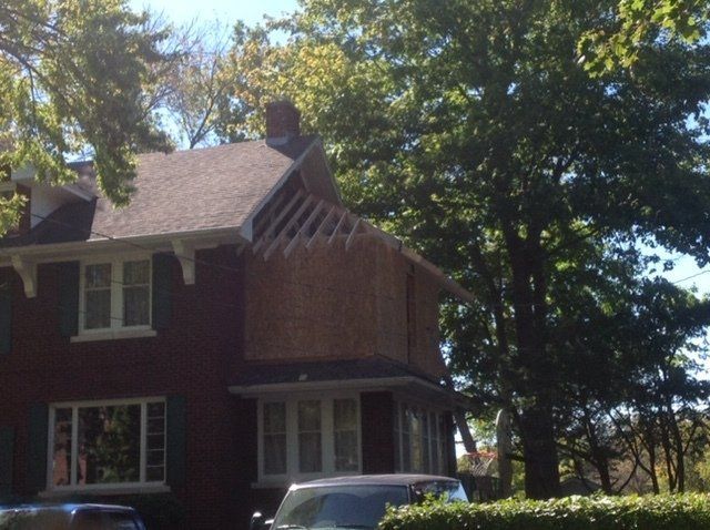Brick house with white-trimmed windows, surrounded by trees in bright sunlight