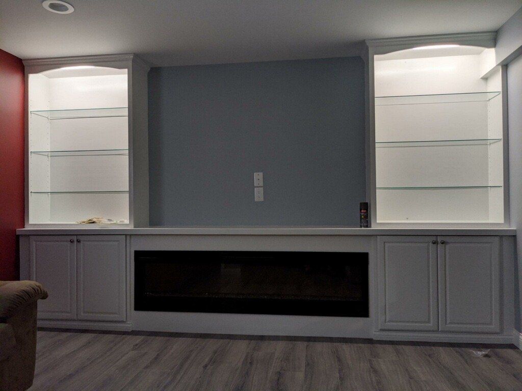 Gray living room wall with built-in cabinets, mirrored shelves, and a black electric fireplace
