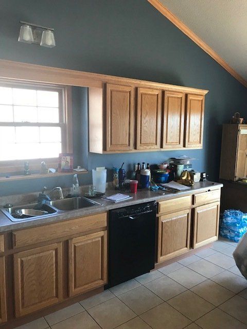 Small kitchen with wood cabinets, black appliances, tiled floor, and a window over the sink.
