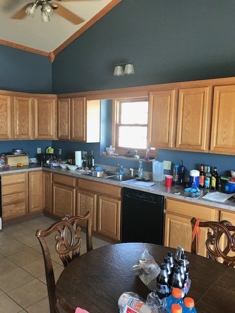 Kitchen with wood cabinets, blue walls, tiled floor, and a round dining table in the foreground.