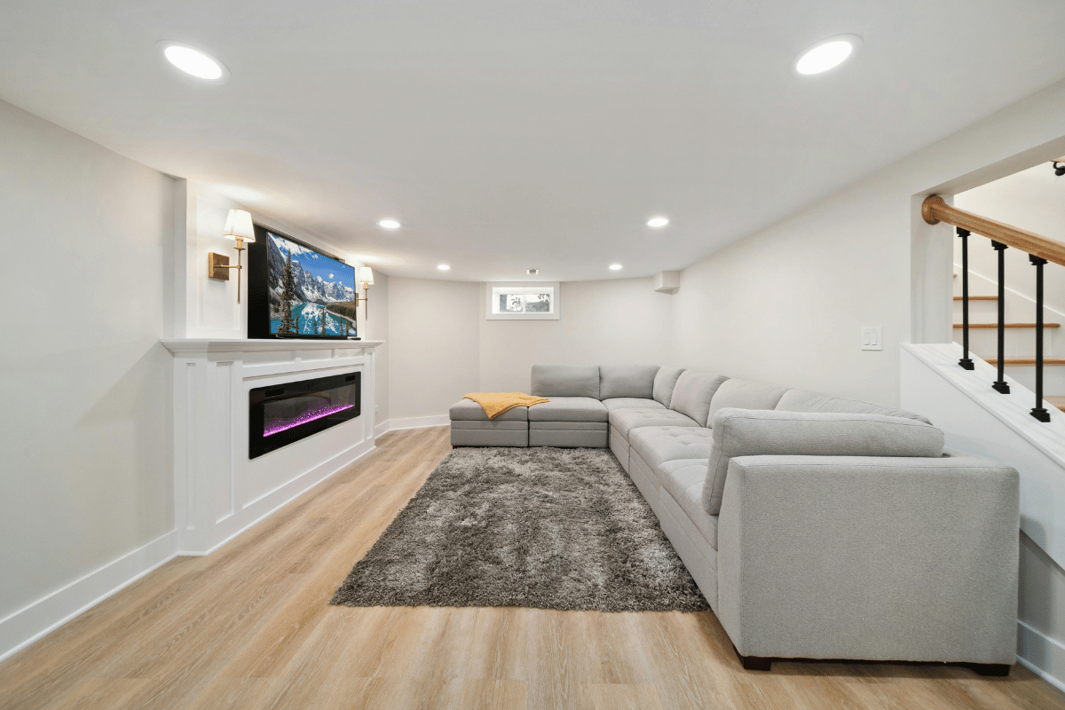 Bright modern living room with gray sectional, fireplace, wall TV, and wood flooring