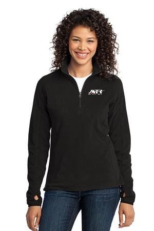 A person wearing a black quarter-zip fleece pullover with a small white logo on the chest and thumbholes on the sleeves.