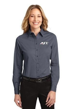 A person smiling while wearing a dark grey, long-sleeved button-down shirt with a white logo on the chest.