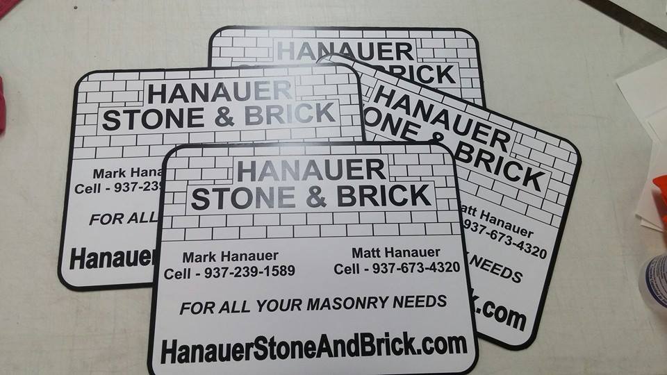 Four rectangular business magnets for Hanauer Stone & Brick featuring contact information stacked on a white surface.