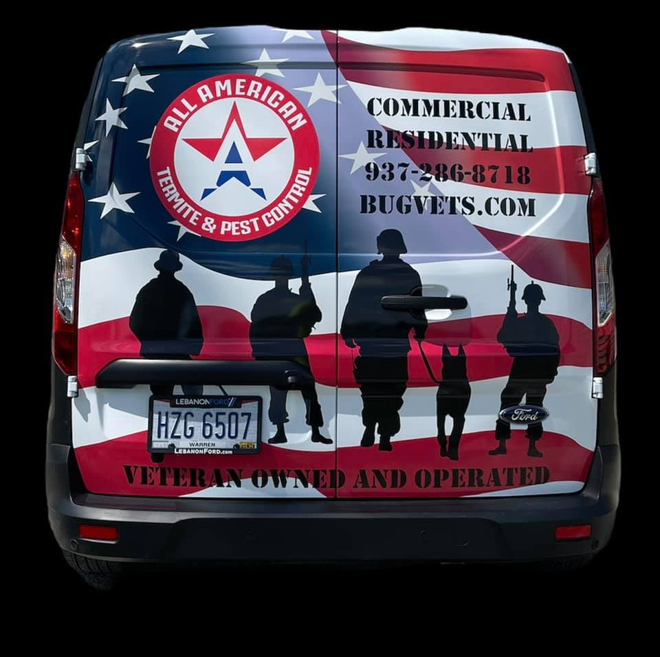 Rear view of a work van wrapped in an American flag design with service silhouettes, contact info, and company branding.