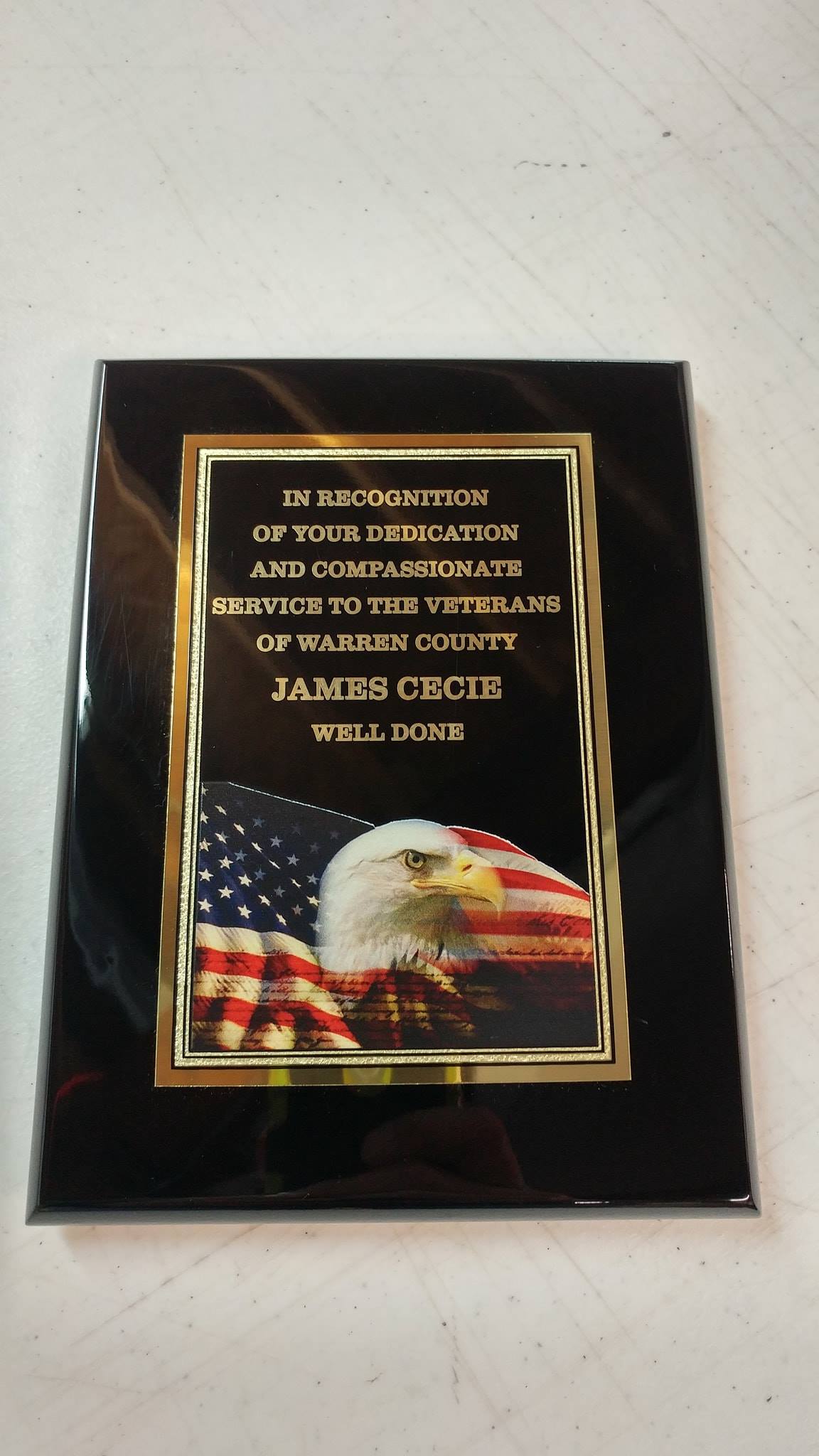 A black award plaque featuring an American flag, a bald eagle, and text honoring service to Nassau County veterans.