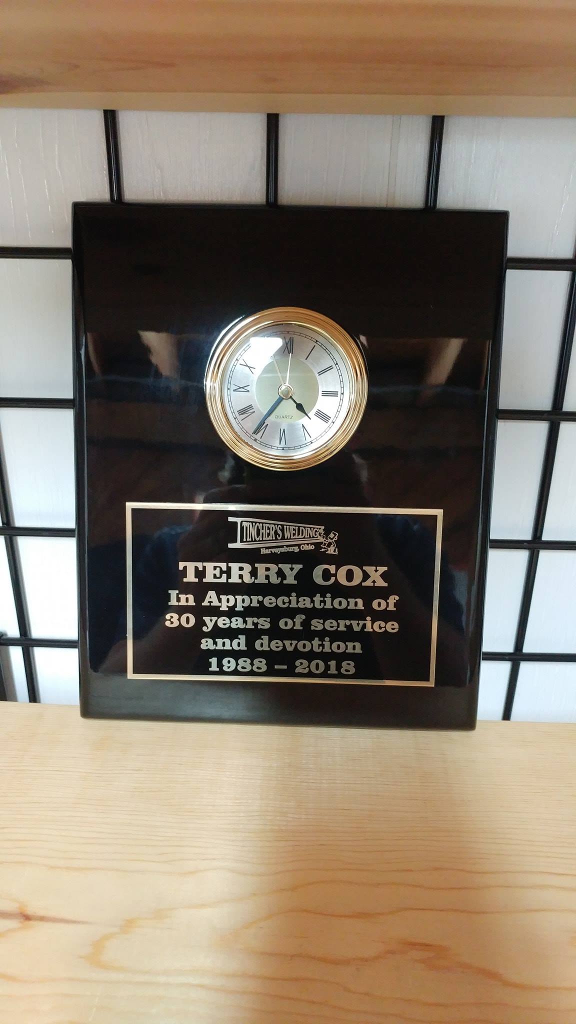 A plaque honoring Terry Cox for 40 years of service, featuring a small clock mounted on a black rectangular base.