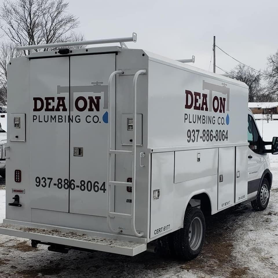 A white Deaton Plumbing service truck parked in a snowy setting, displaying the company name and phone number.