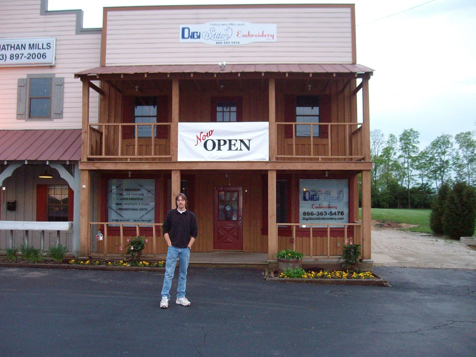 A person stands in front of a two-story wooden building with a balcony and an 
