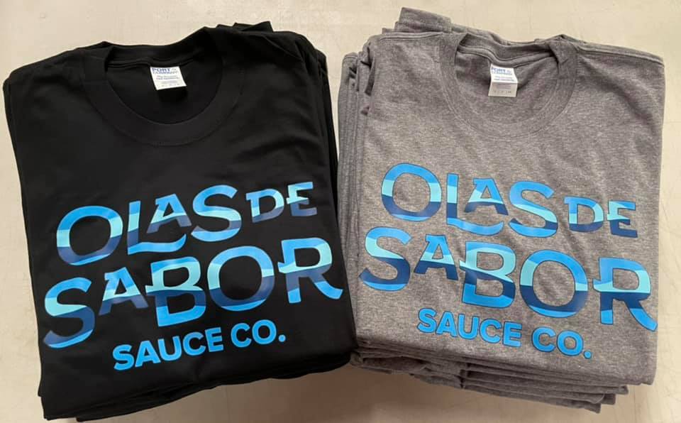 A black t-shirt and a stack of grey t-shirts, each printed with blue