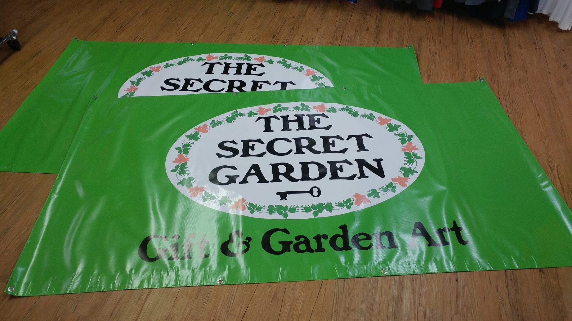 Two bright green vinyl banners on a wooden floor, both featuring the text