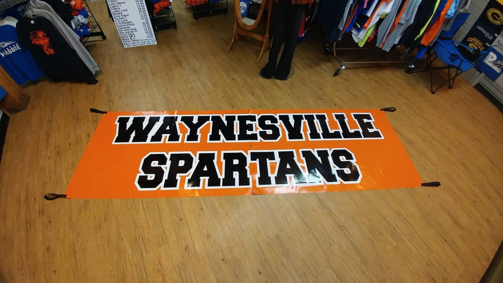 An orange horizontal banner on a wooden floor reading