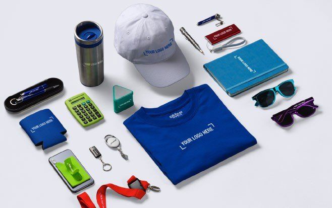 A collection of branded promotional items, including a blue t-shirt, a white cap, a notebook, and various accessories.