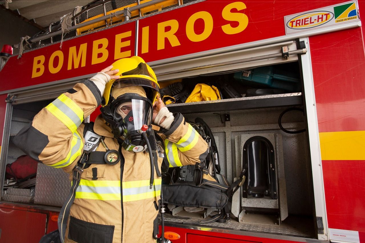 Um bombeiro está usando uma máscara de gás na frente de um caminhão de bombeiros.