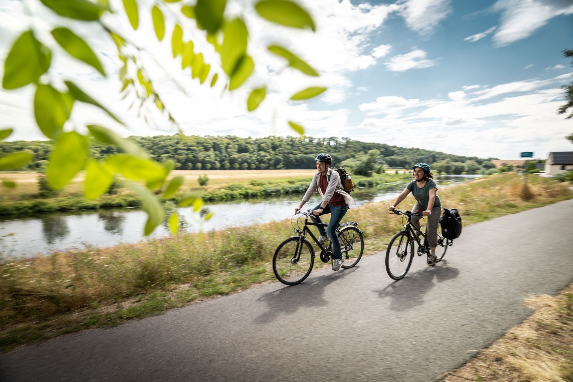 2 Radfahrer auf dem Mulderadweg unterwegs, im Hintergrund ist die Mulde zu sehen
