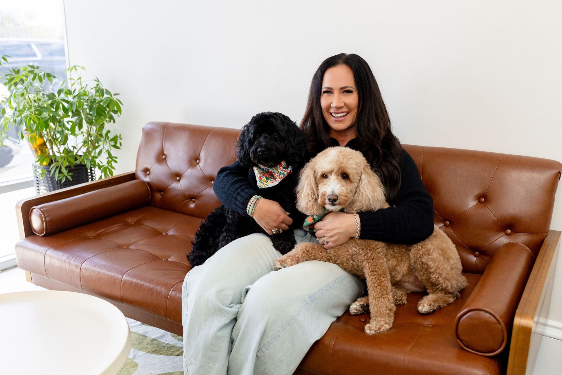 A woman is sitting on a couch with two dogs.