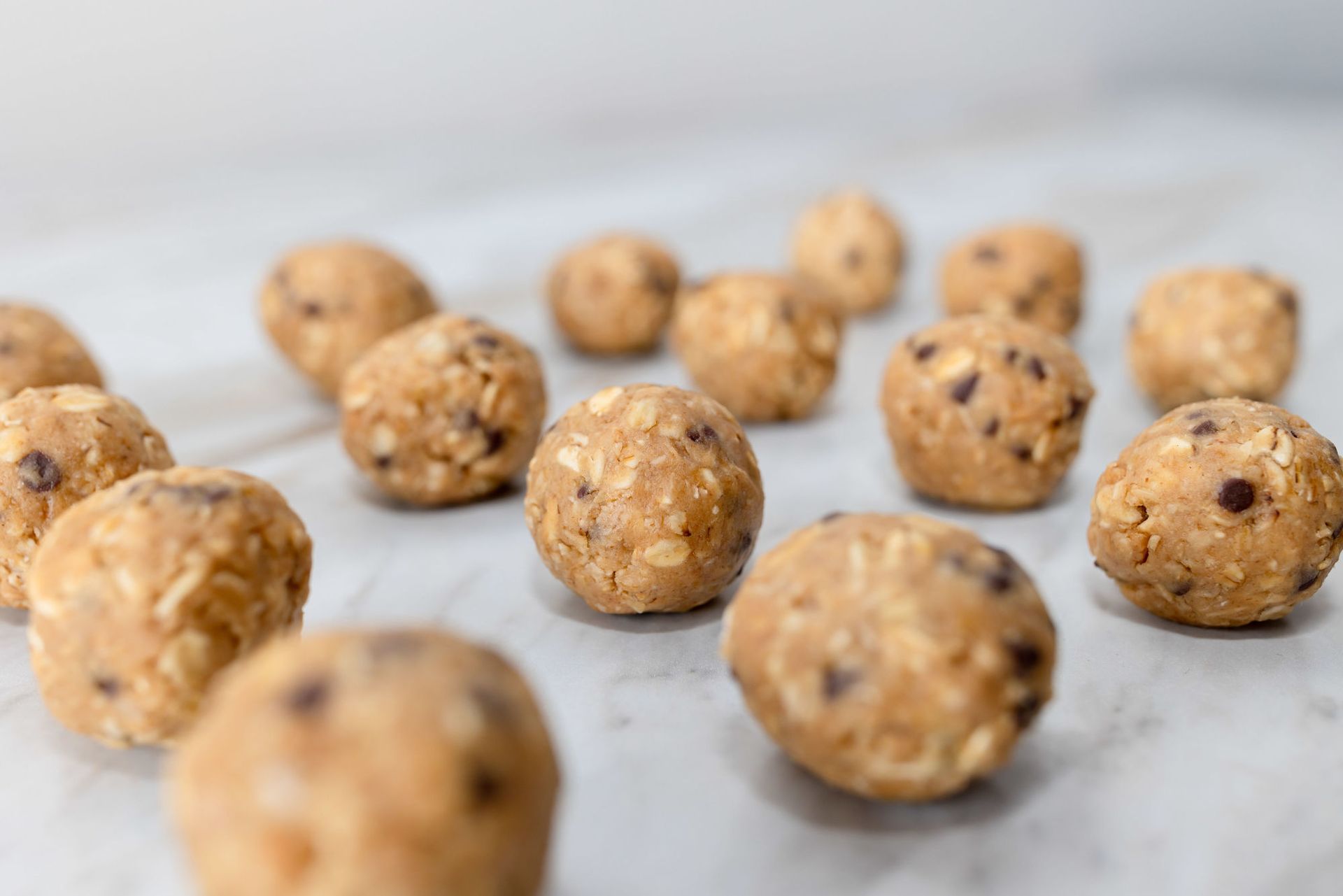 A bunch of peanut butter balls with chocolate chips on a table.