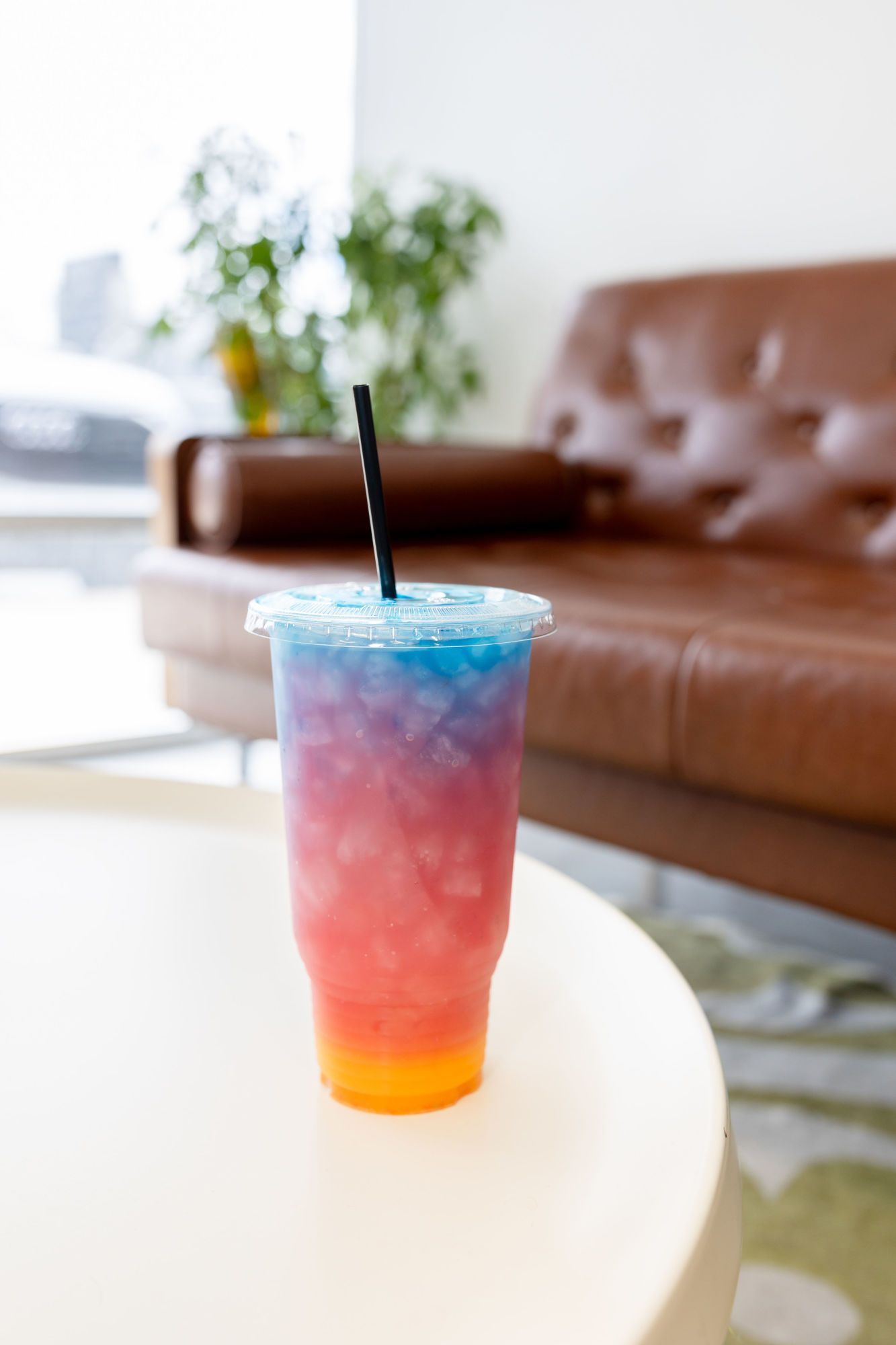 A colorful drink in a plastic cup with a straw on a table.